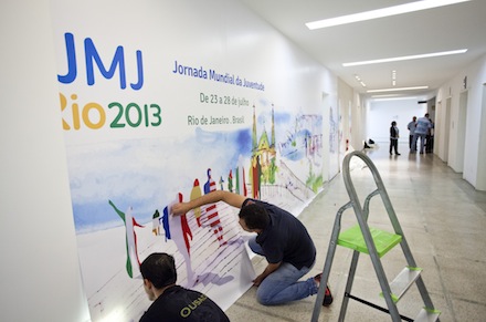 World Youth Day volunteers put up a poster in a building in Rio (CNS)
