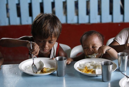 Two brothers eat a meal provided by a charity in a slum in Manila (CNS)